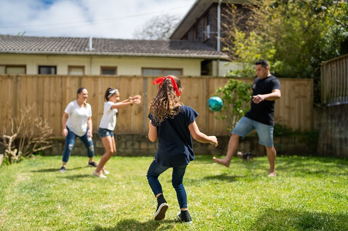 Photo of mother and children in yard playing with a ball with dad